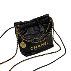 Black quilted mini hobo crossbody bag with gold chain trim, Chanel logo panel, and drawstring.