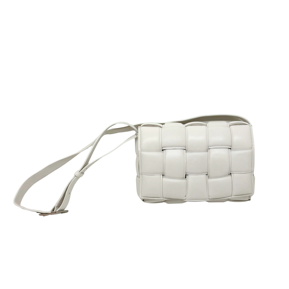 White leather crossbody bag side view with thin shoulder strap and panel detailing