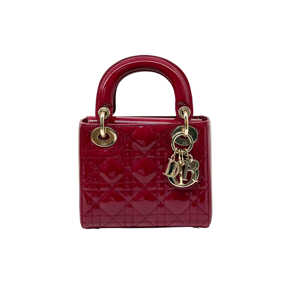 Red quilted patent handbag with gold top handles and dangling monogram charm