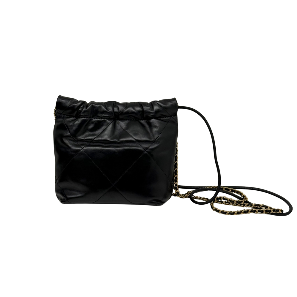 Black quilted mini crossbody bag with gold chain strap, side view.