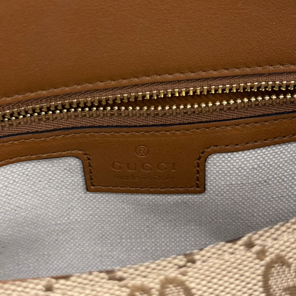 Gucci brown leather label and zipper detail on GG canvas bag