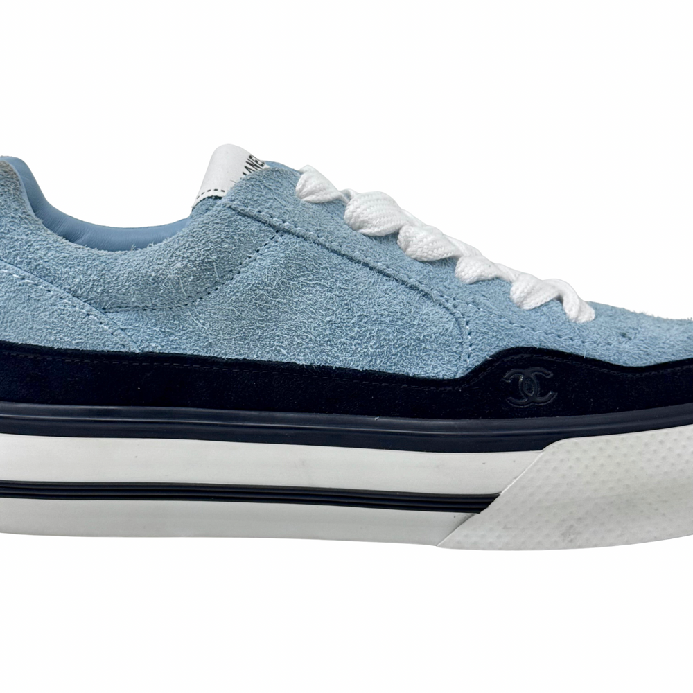 Blue suede sneaker side profile with small CHANEL emblem on black trim