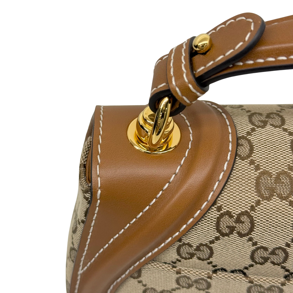 Tan leather handle strap with gold-tone hardware attachment and stitching