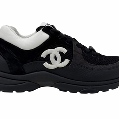 Black sneakers with large white Chanel CC logo on side and chunky outsole.