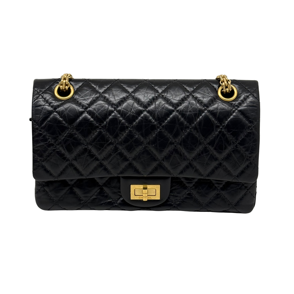 Black quilted shoulder bag with gold top rings, center turn-lock flap closure