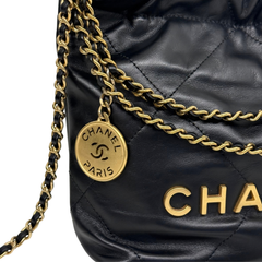 Black quilted mini crossbody bag with gold chain strap and round Chanel logo charm.