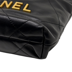 Black quilted mini crossbody bag corner with gold “CHANEL” lettering on the flap.