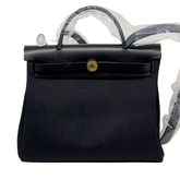 Hermes handbag front view with round gold clasp, textured body, and top handles