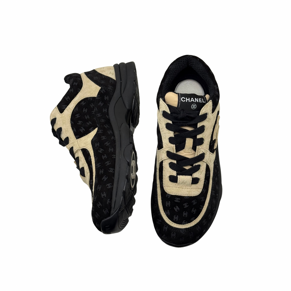 Black and beige Chanel low-top sneakers with lace-up closure and chunky rubber sole