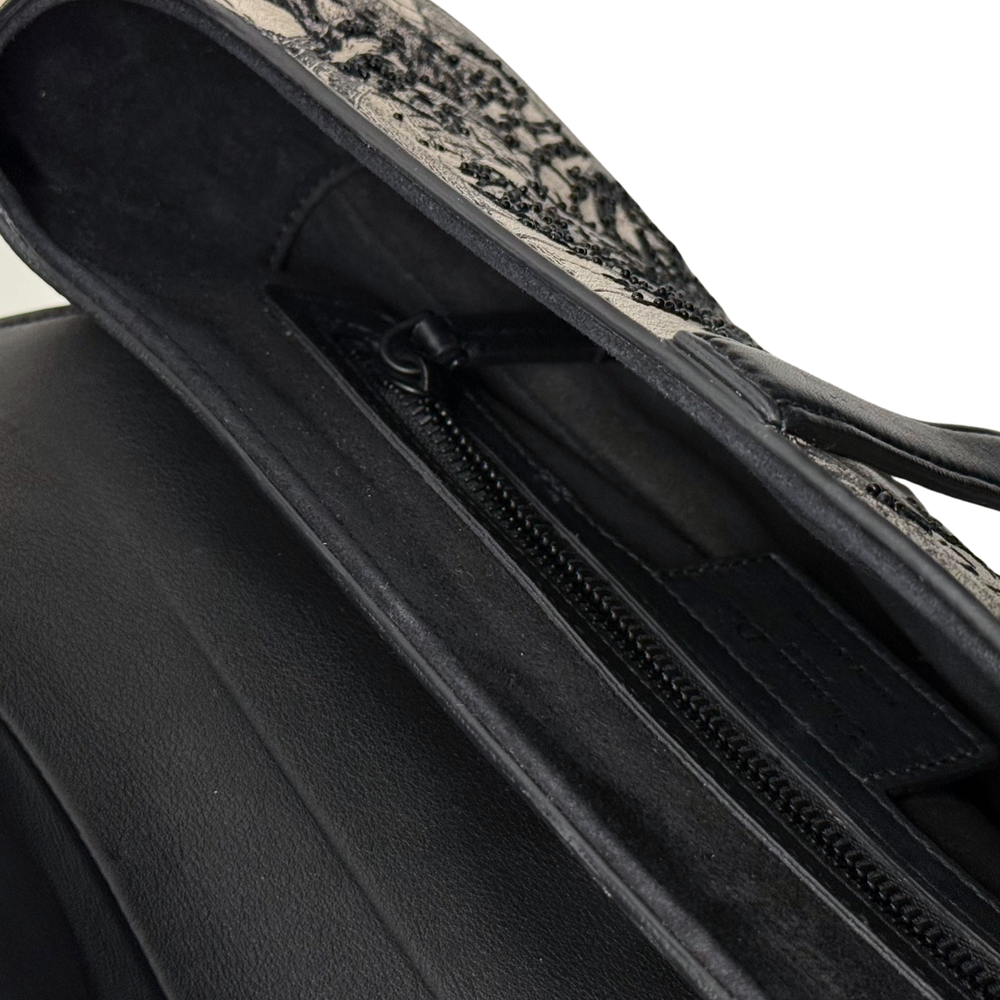 Christian Dior saddle bag interior view showing black zipper track and black lining.