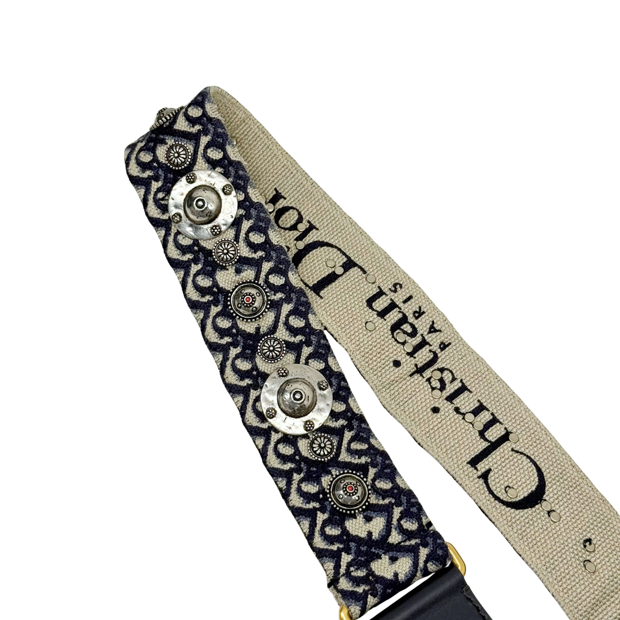 Patterned shoulder strap with beige webbing, dark fabric, and silver grommets