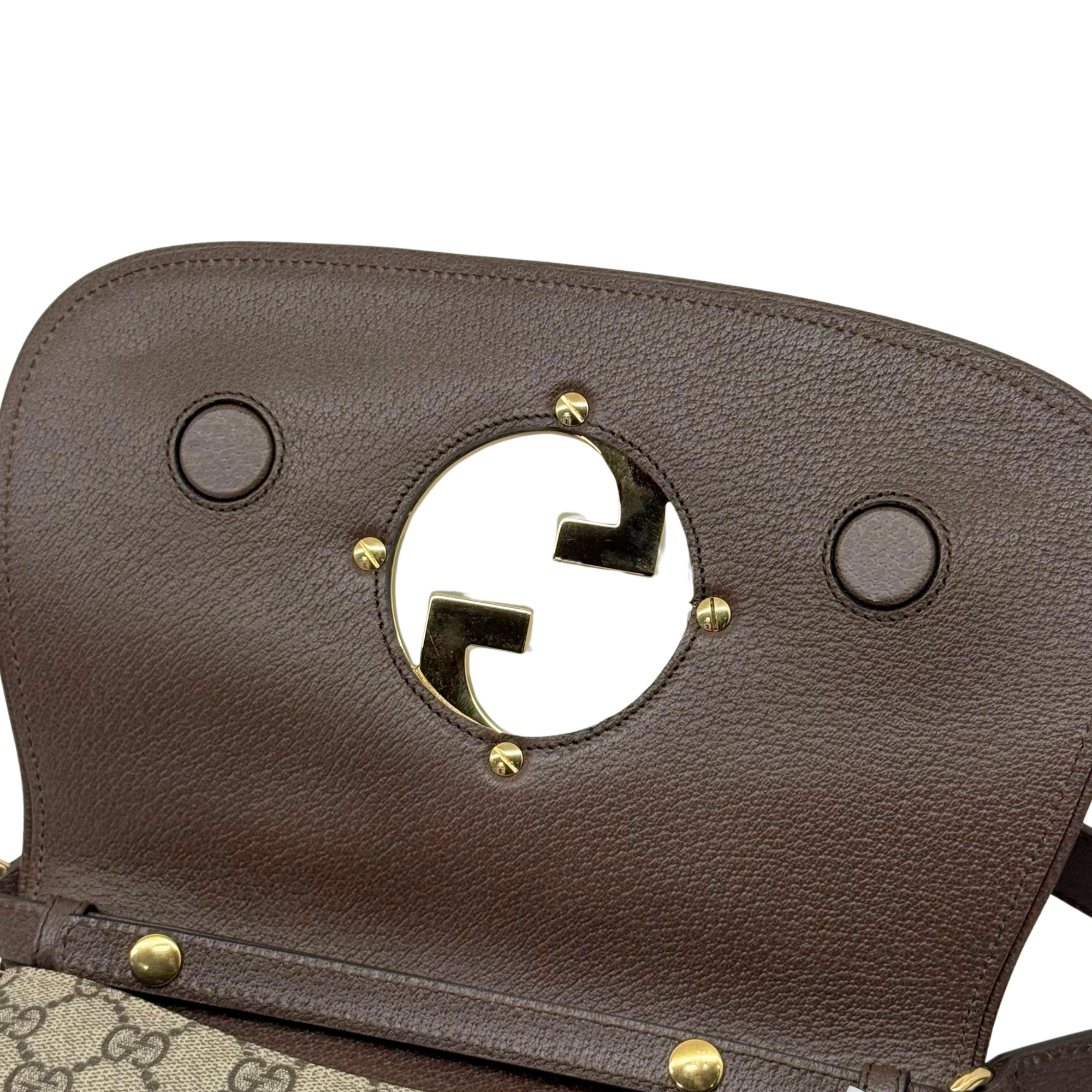 Gucci flap crossbody bag in textured brown leather with gold-tone G emblem and snap studs