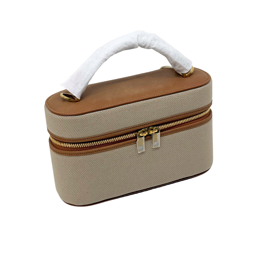 Beige top-handle vanity bag with brown leather trim and centered gold zipper
