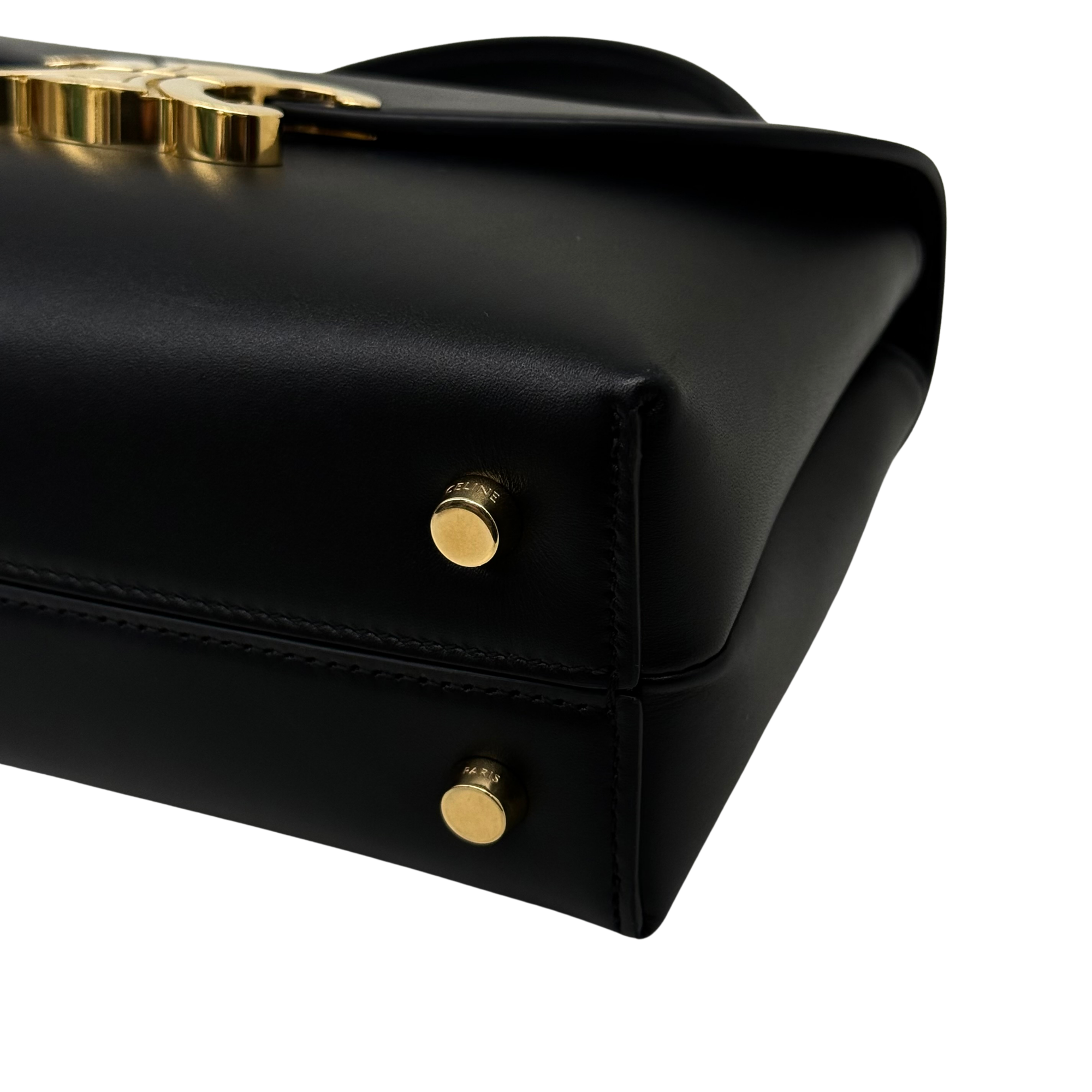 Black leather flap bag side panel with gold snap buttons and embossed strap