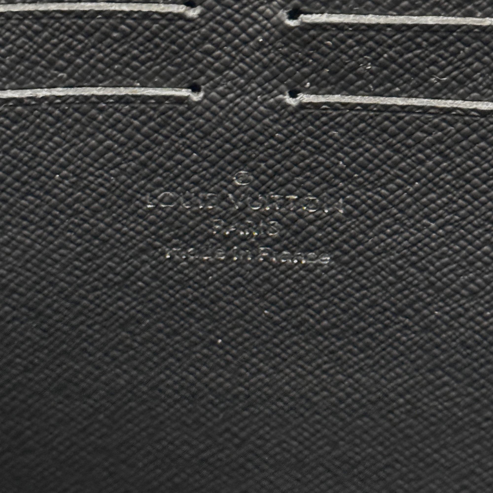 Louis Vuitton textured black leather wallet close-up with small embossed logo detail