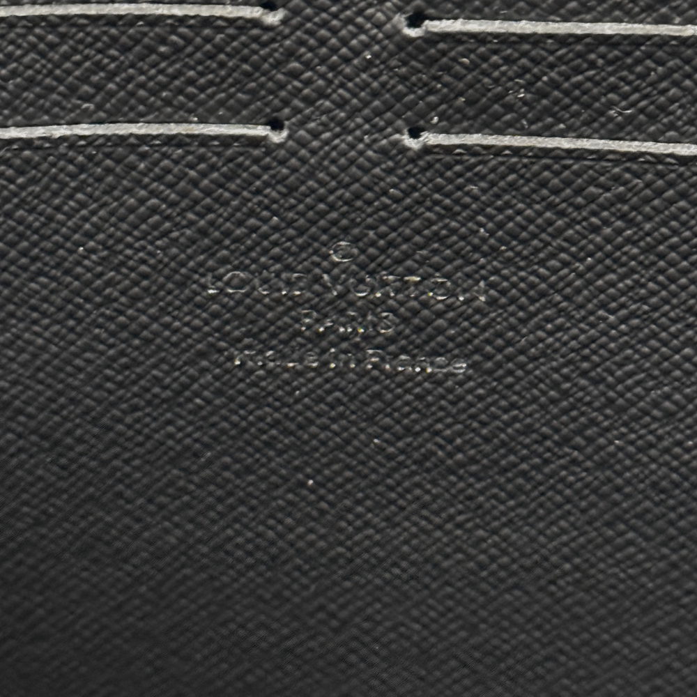 Louis Vuitton textured black leather wallet close-up with small embossed logo detail