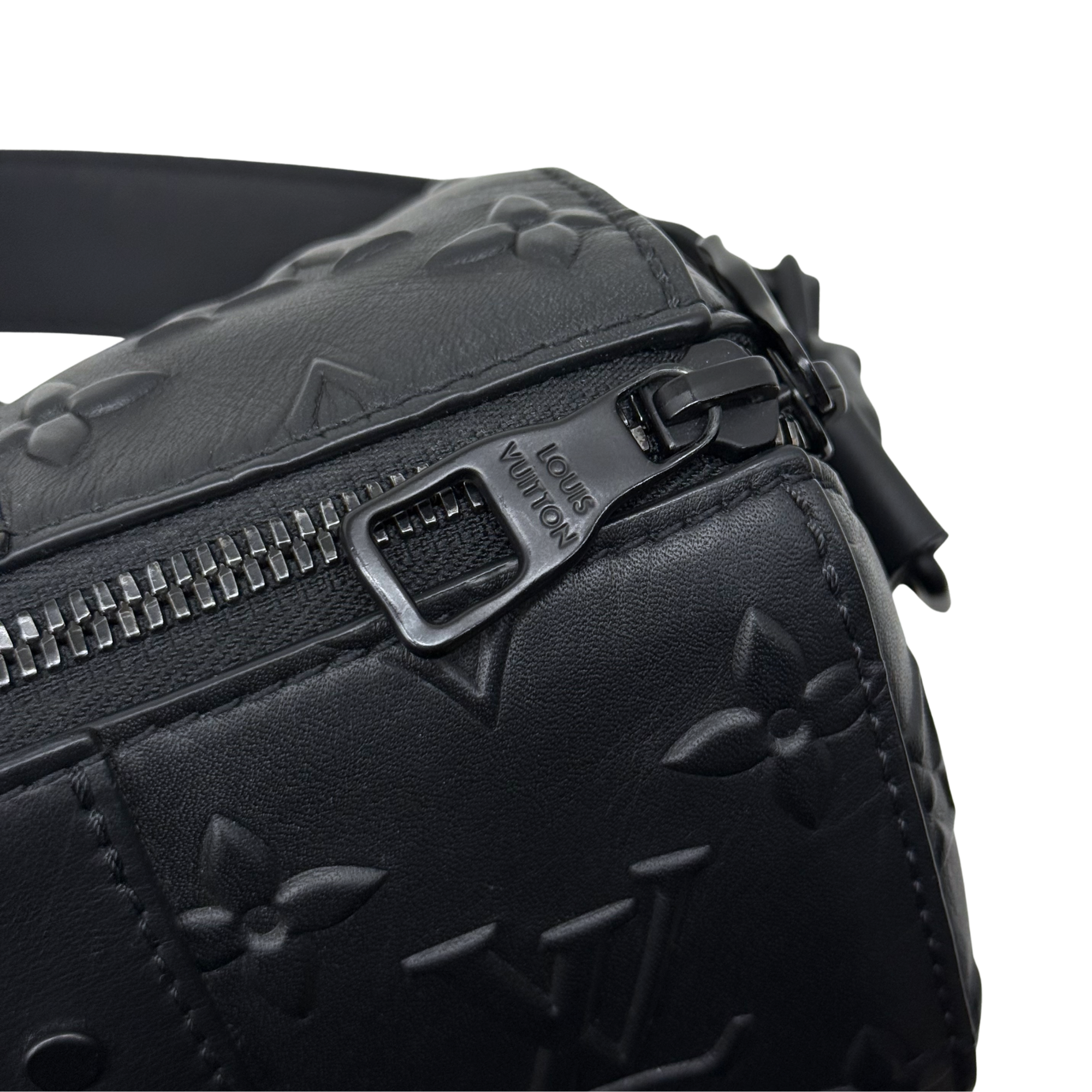 Black Louis Vuitton monogram bag zipper with engraved metal pull, close-up
