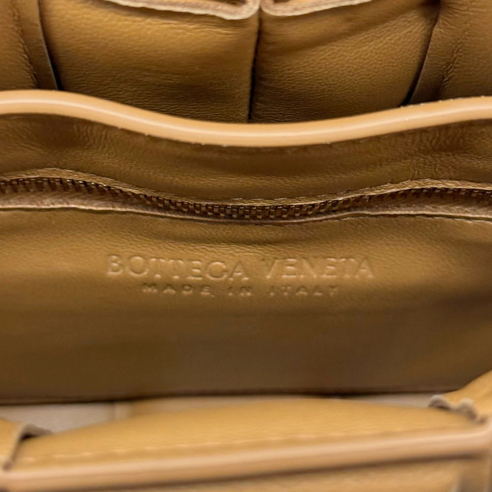Tan leather bag with embossed logo panel and stitched top zipper trim