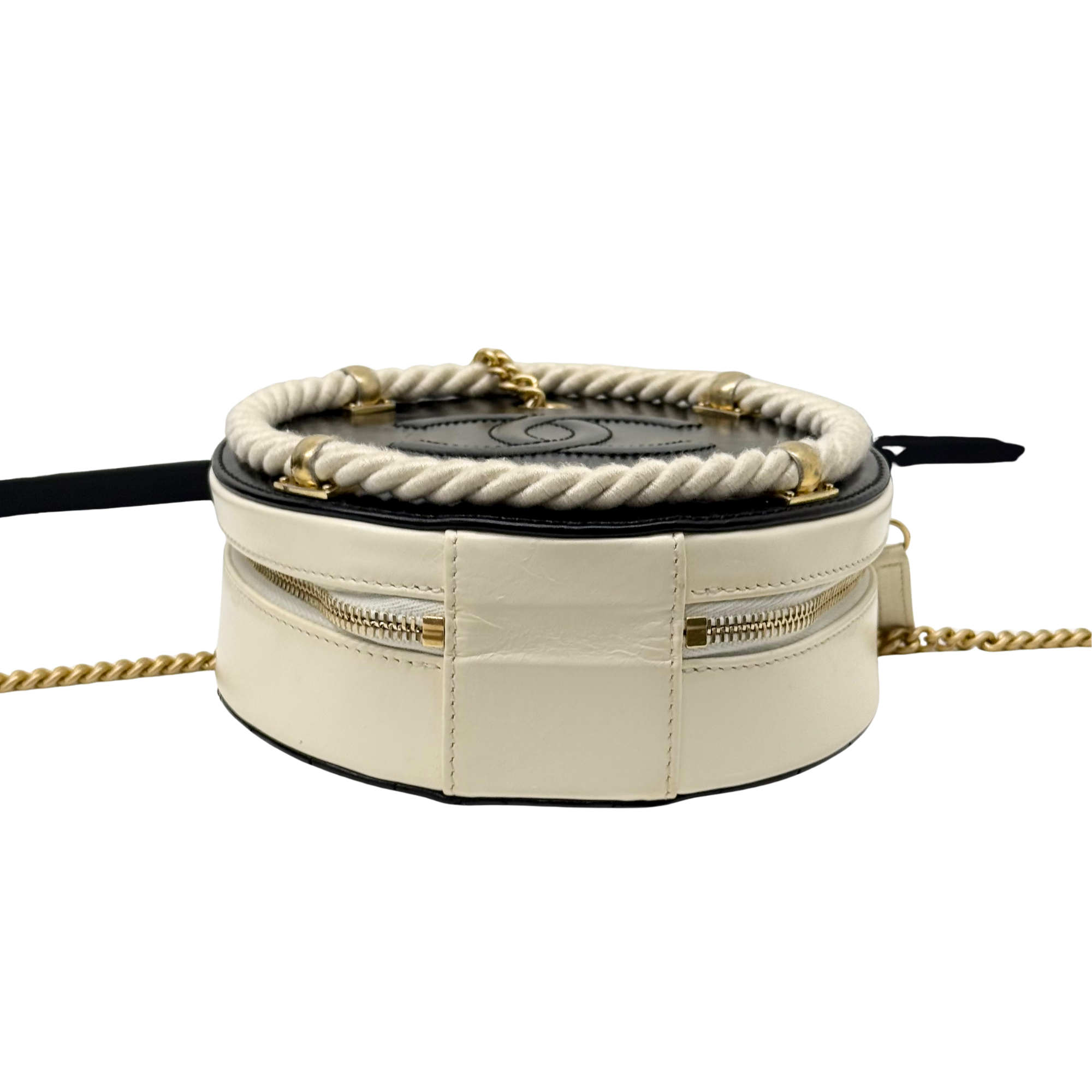 Back view of cream round crossbody bag with braided top edge and gold zippers