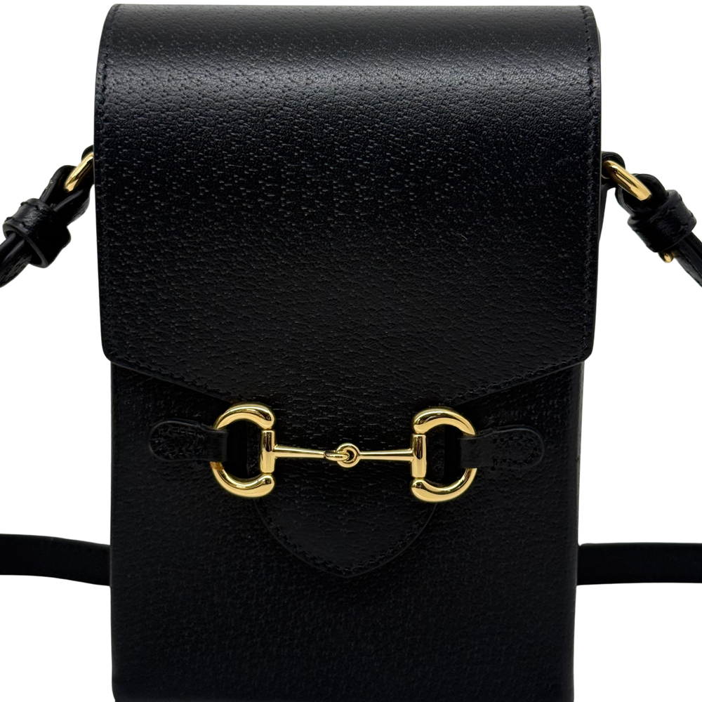 Black leather crossbody bag close-up of gold horsebit hardware