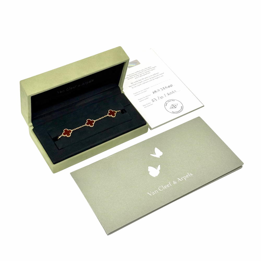 Goldtone bracelet with five red clover motifs, shown in gift box
