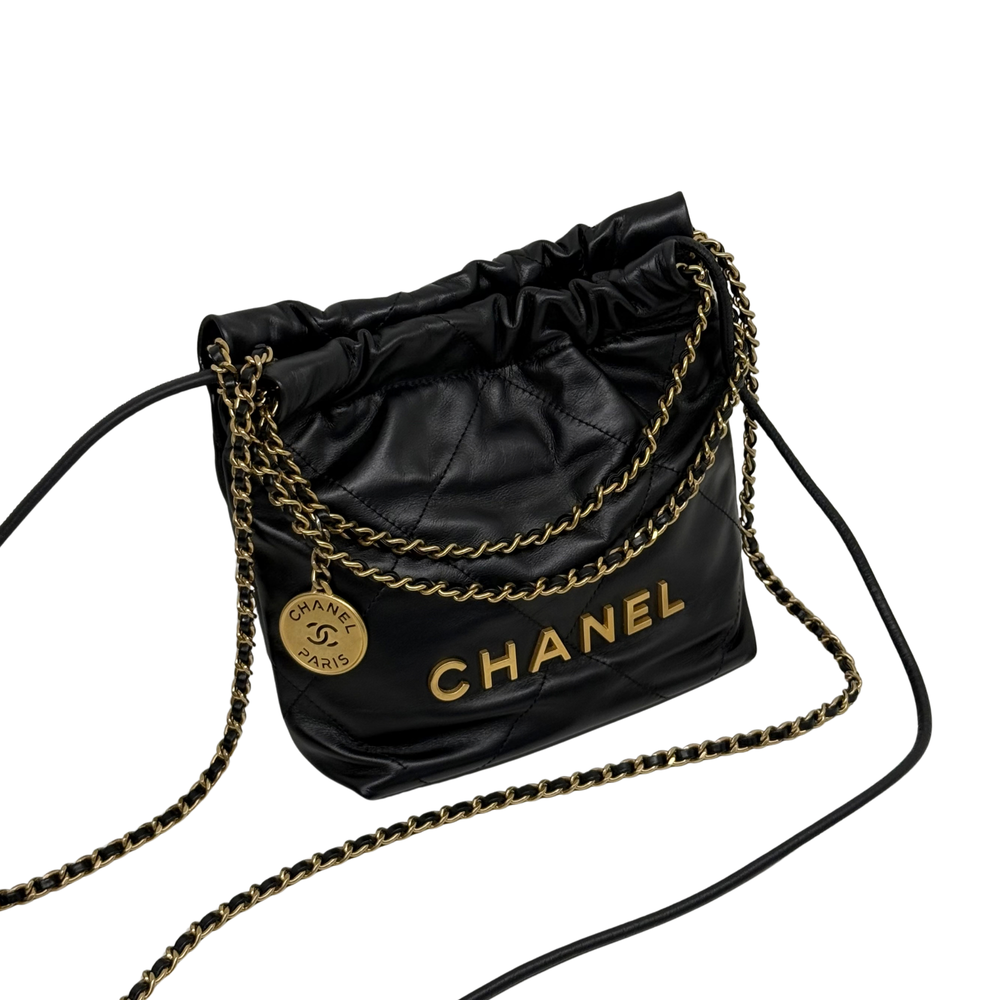 Black quilted mini hobo crossbody bag with gold chain trim, Chanel logo panel, and drawstring.