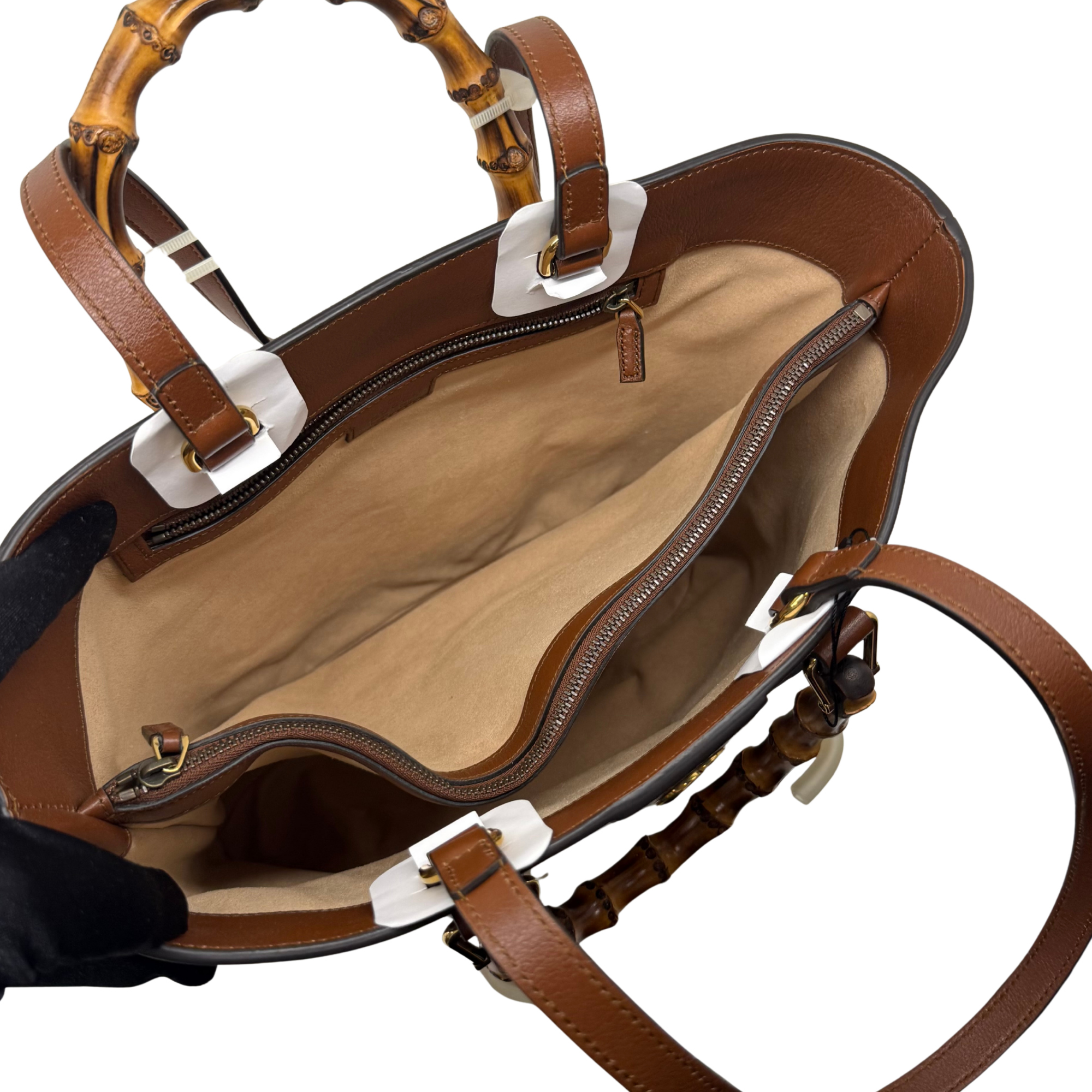 Open brown Gucci tote with beige interior, top zipper, and leather shoulder straps