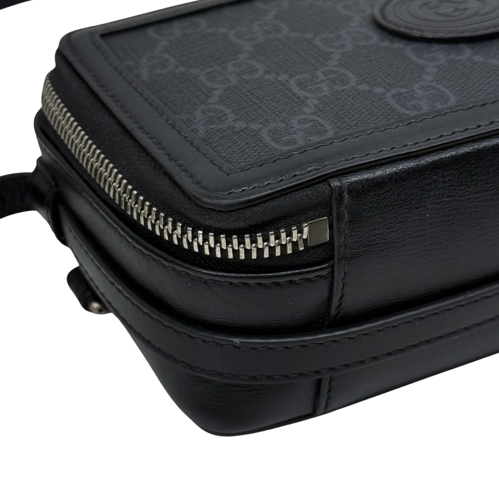 Small crossbody bag close-up, silver-tone zipper, black leather trim and stitching