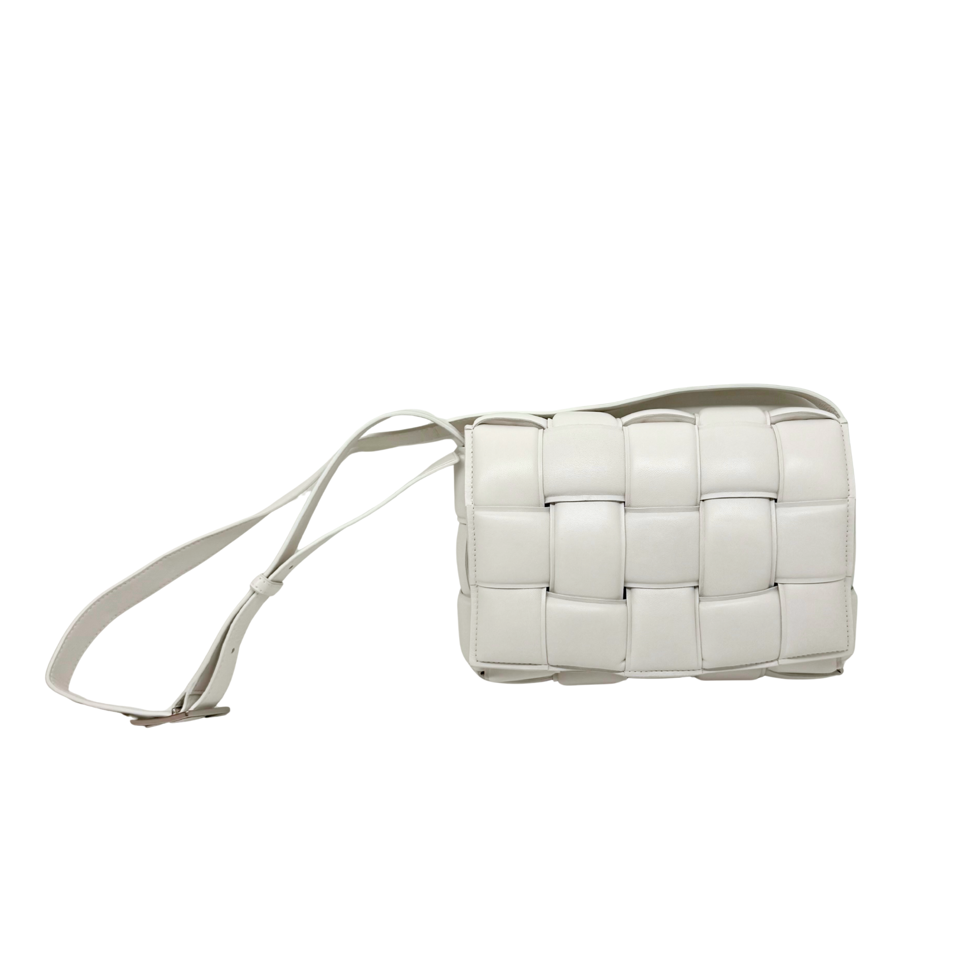 White leather crossbody bag side view with thin shoulder strap and panel detailing