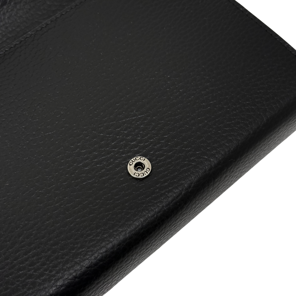 Gucci black leather flap clutch close-up of embossed Gucci logo snap button