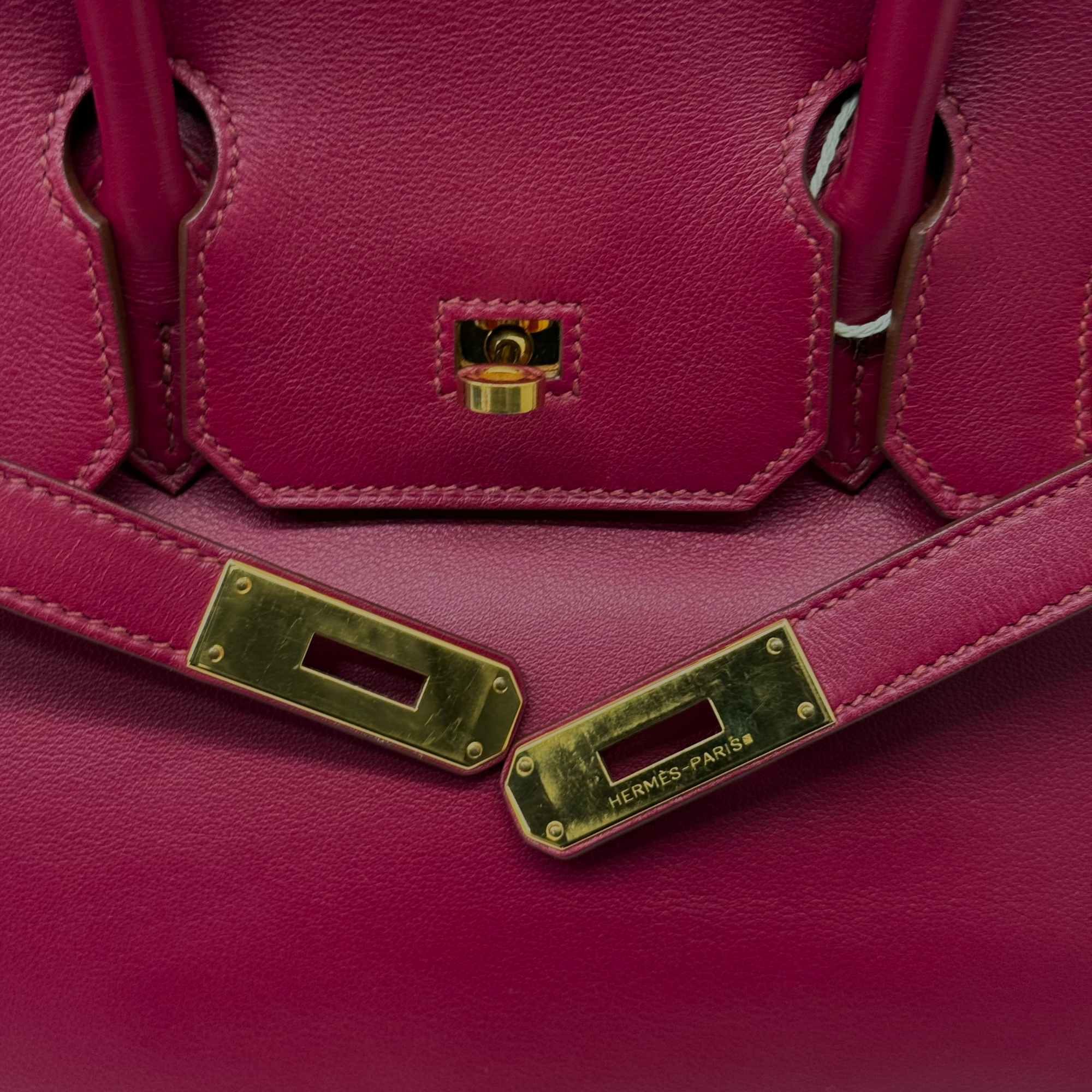 Magenta leather Birkin bag closure plates with gold-tone hardware and HERMES-PARIS
