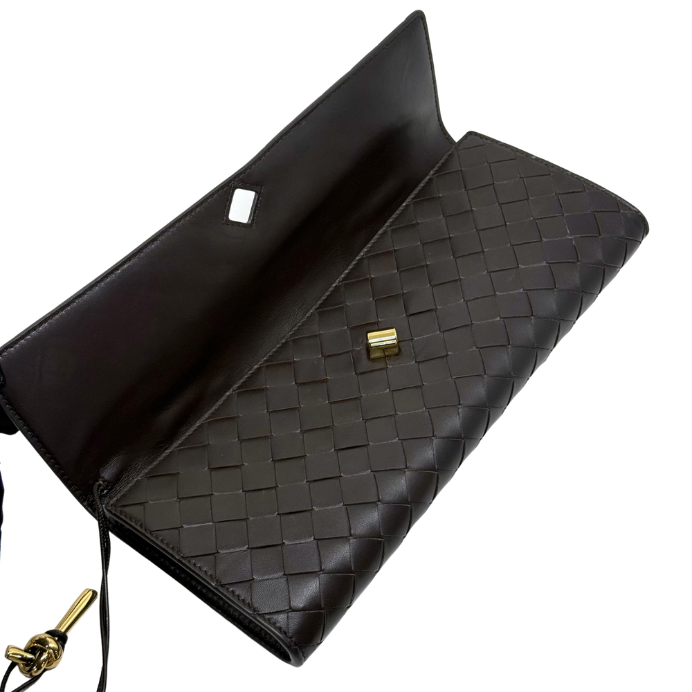 Black woven leather bag with open flap, inner pocket, and gold clasp