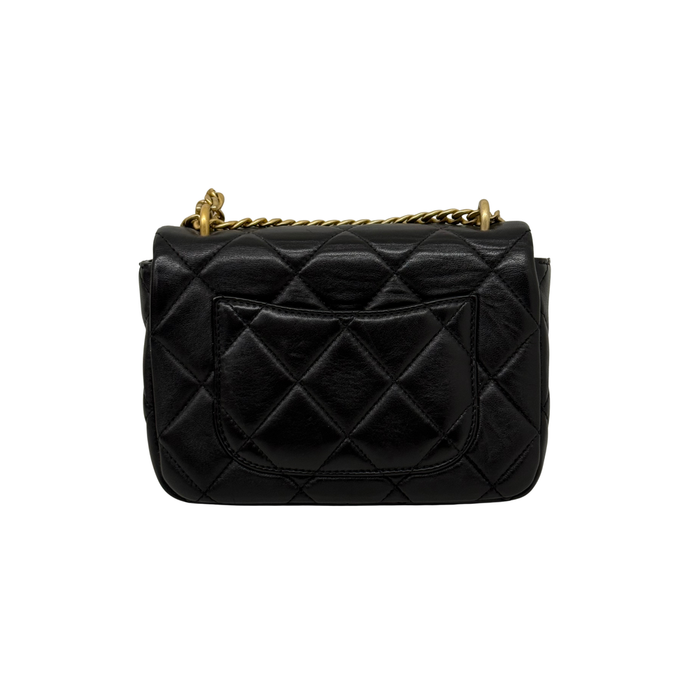 Black quilted shoulder bag with gold-tone chain handle and curved logo medallion