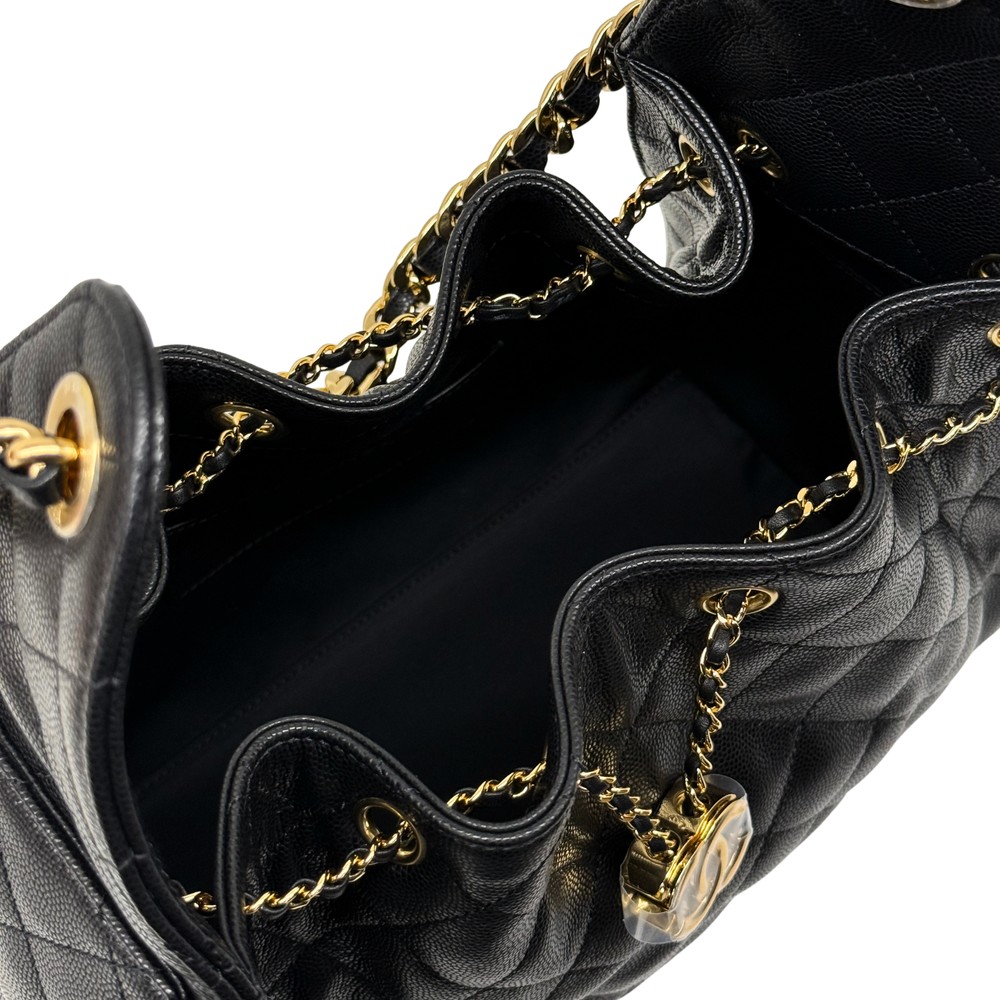 Black quilted handbag interior view with gold chain handles and metal rings