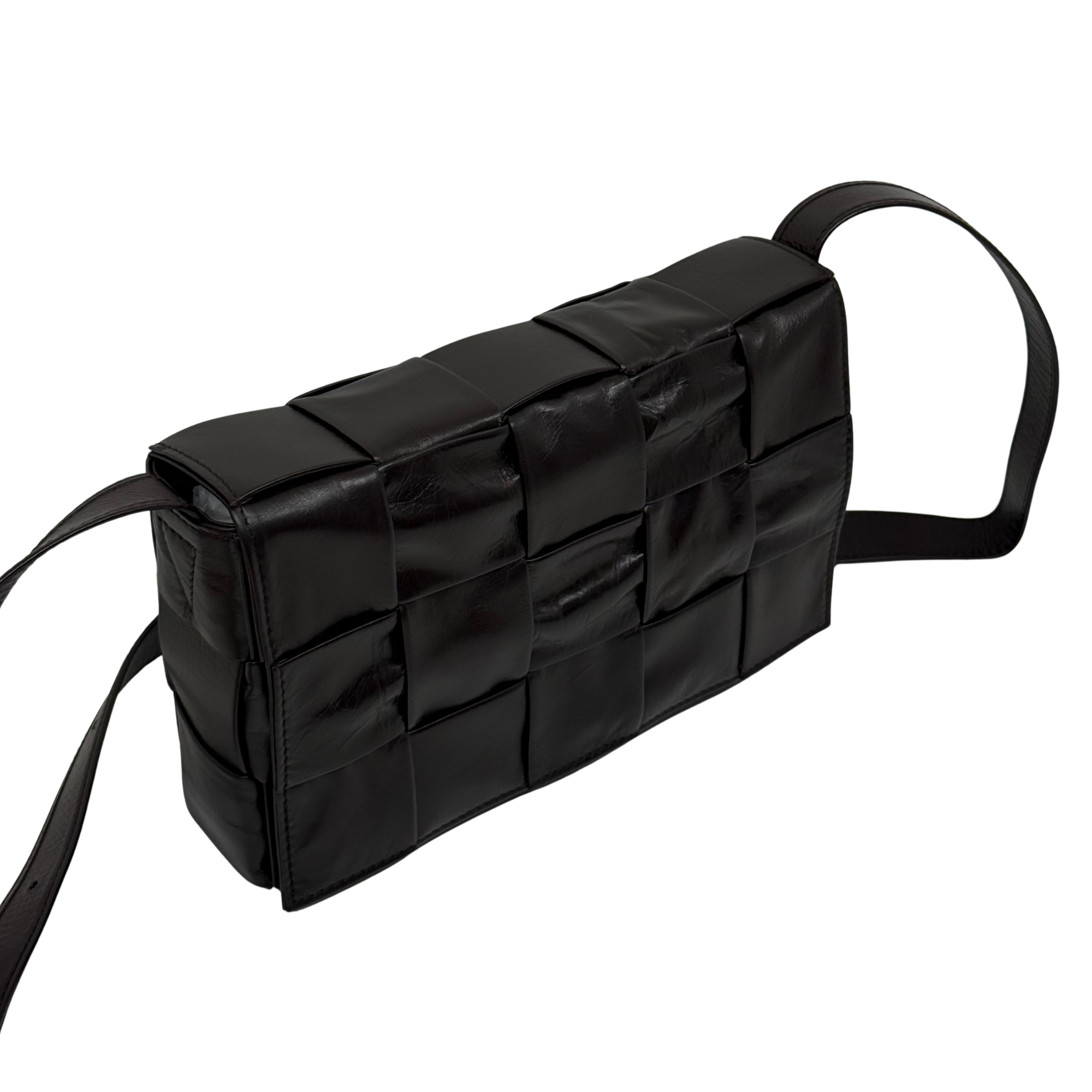 Quilted dark bag with curved side profile and long shoulder strap