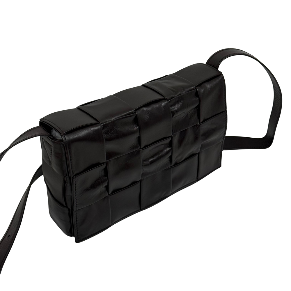 Quilted dark bag with curved side profile and long shoulder strap