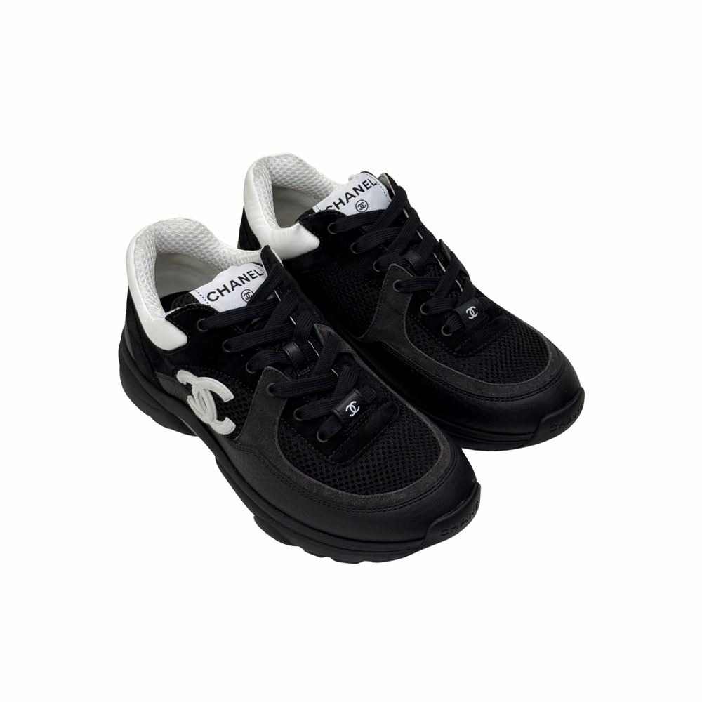 Black lace-up sneakers with white interior collar and Chanel logo on tongue.