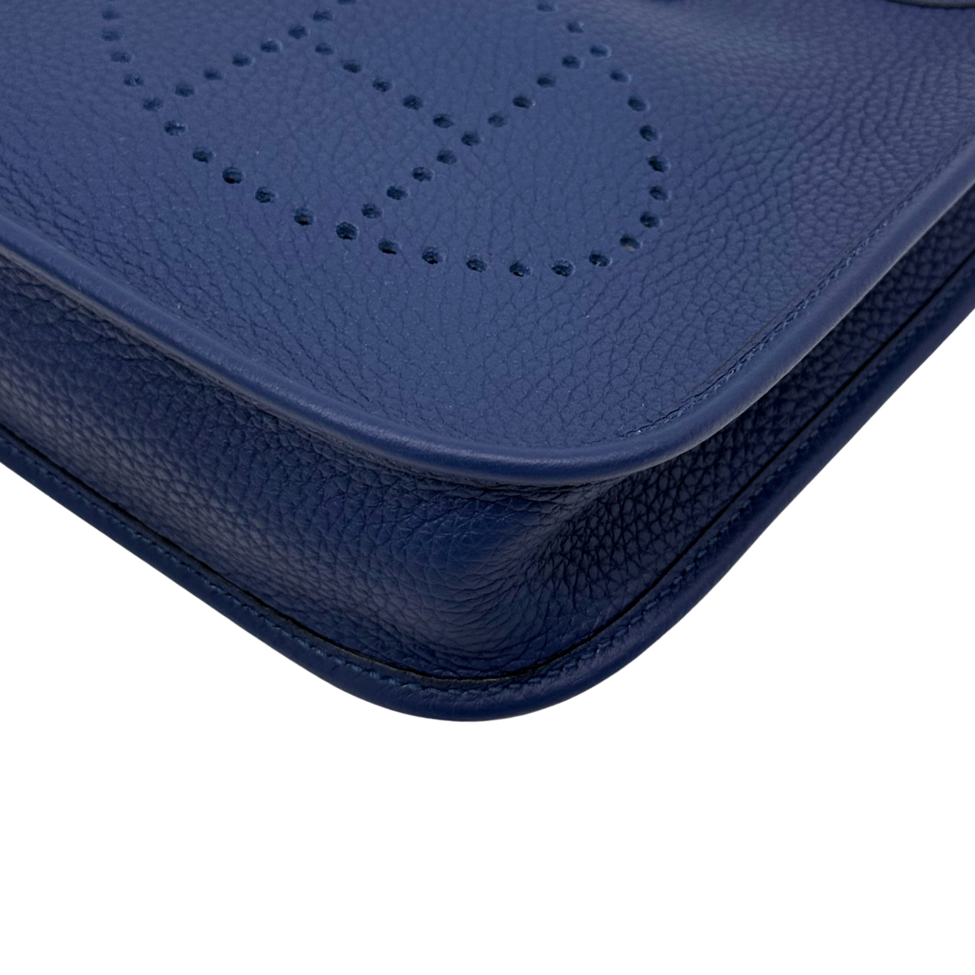 Navy blue front corner of Evelyne 16 crossbody bag with perforated logo panel
