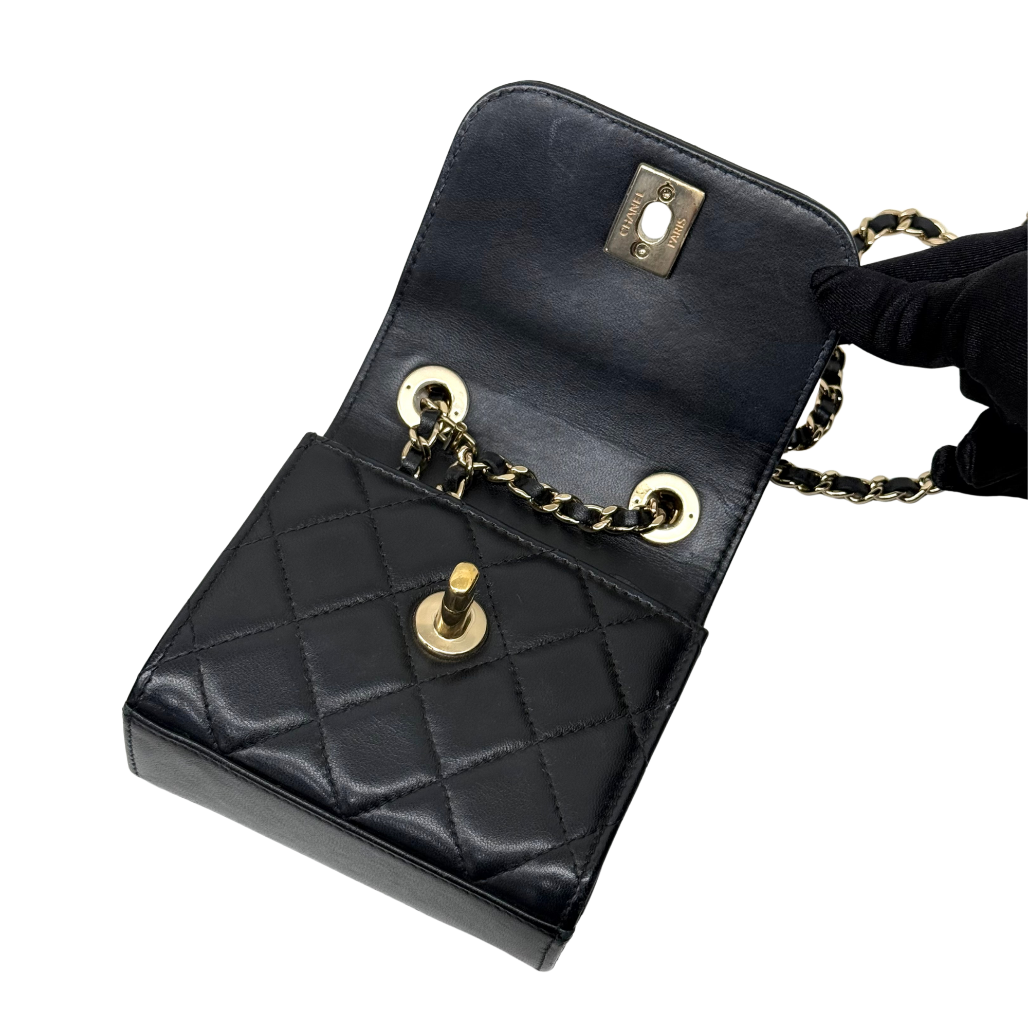 Black Chanel quilted mini flap bag angled view, gold hardware and chain strap