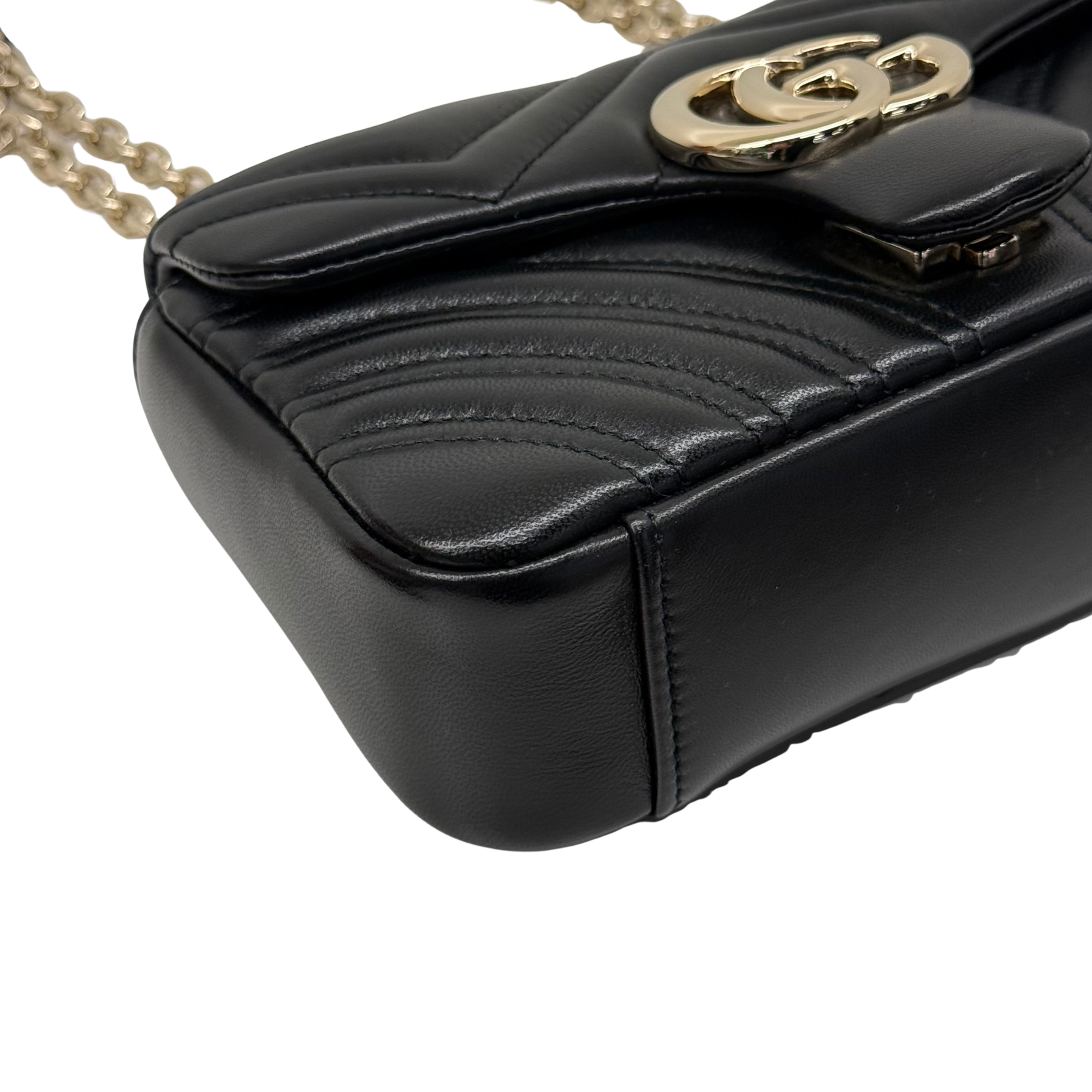 Gucci shoulder bag corner detail with black leather, stitched edges, and gold clasp