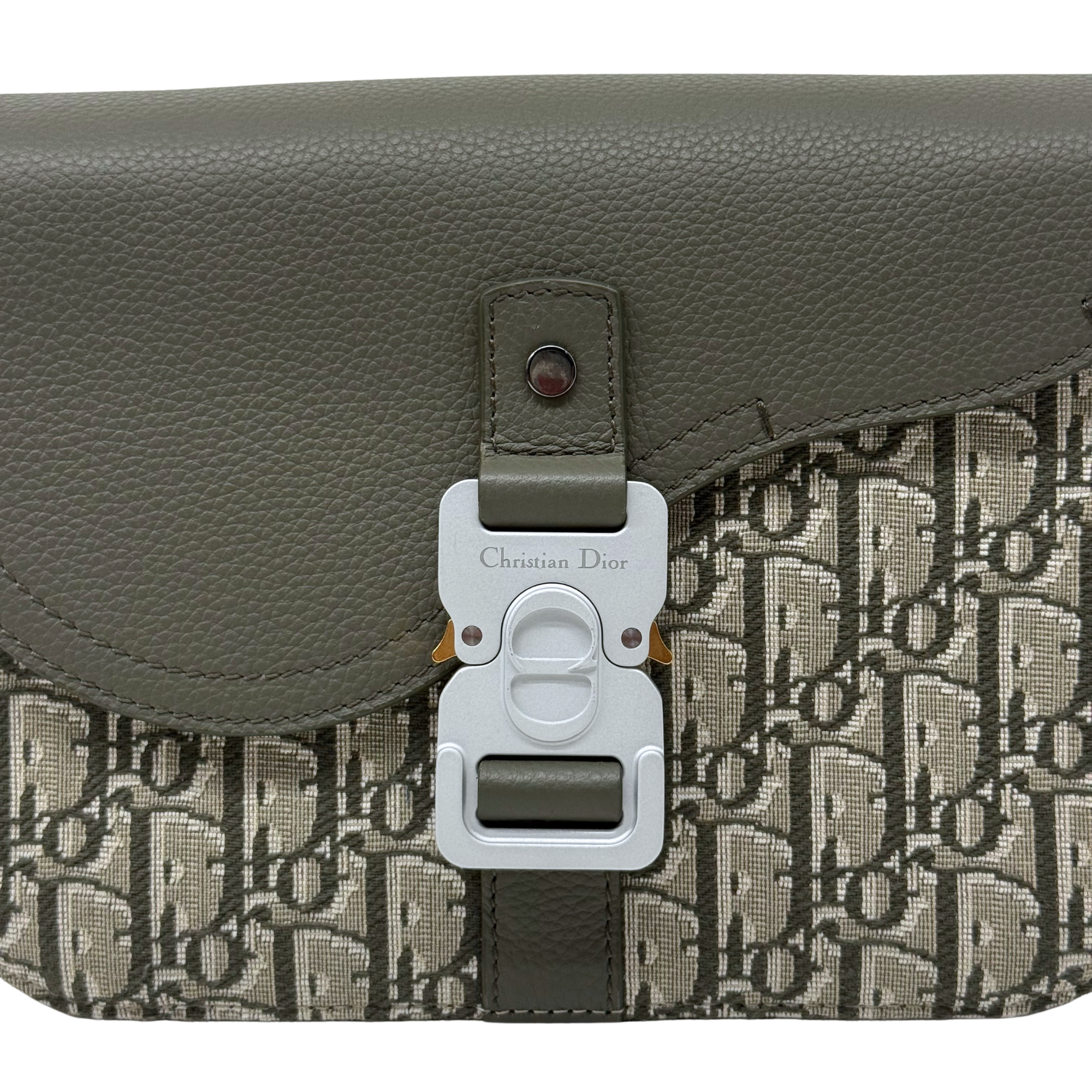 Close-up of Dior logo hardware on olive flap crossbody bag with canvas panel
