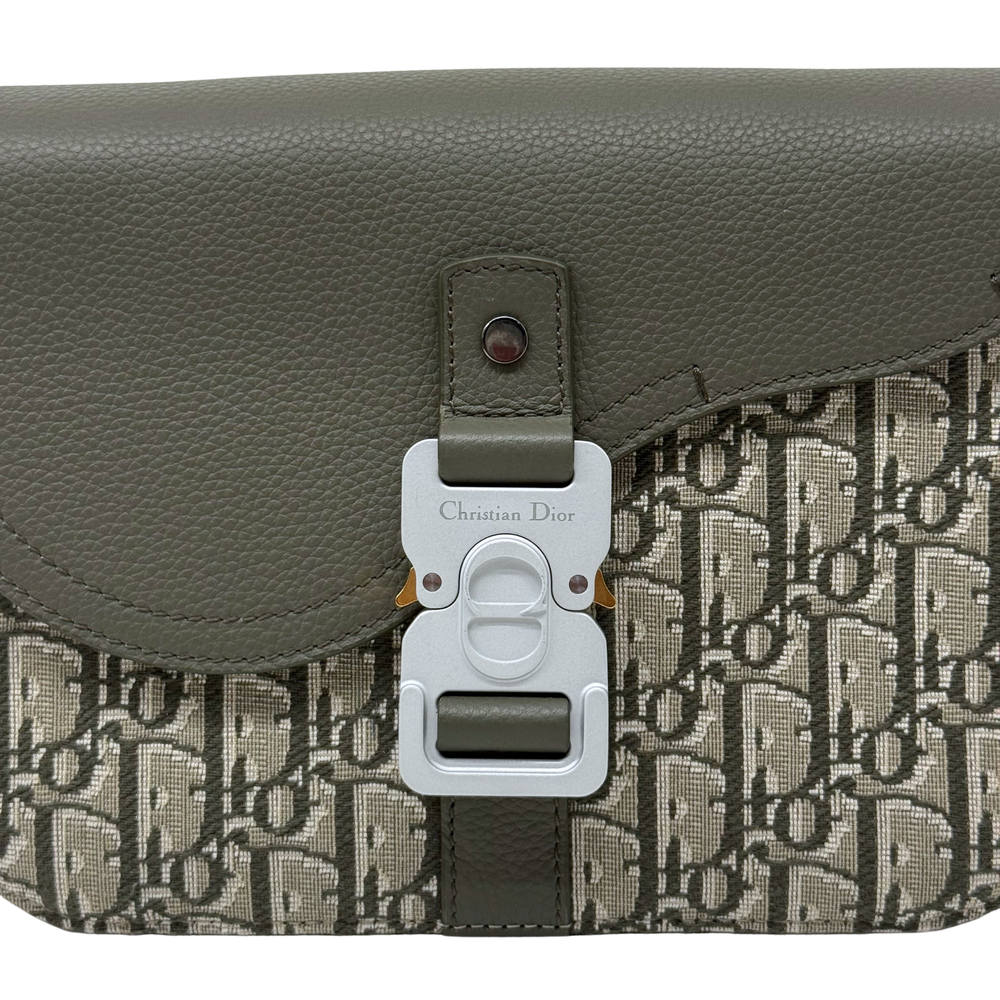 Close-up of Dior logo hardware on olive flap crossbody bag with canvas panel