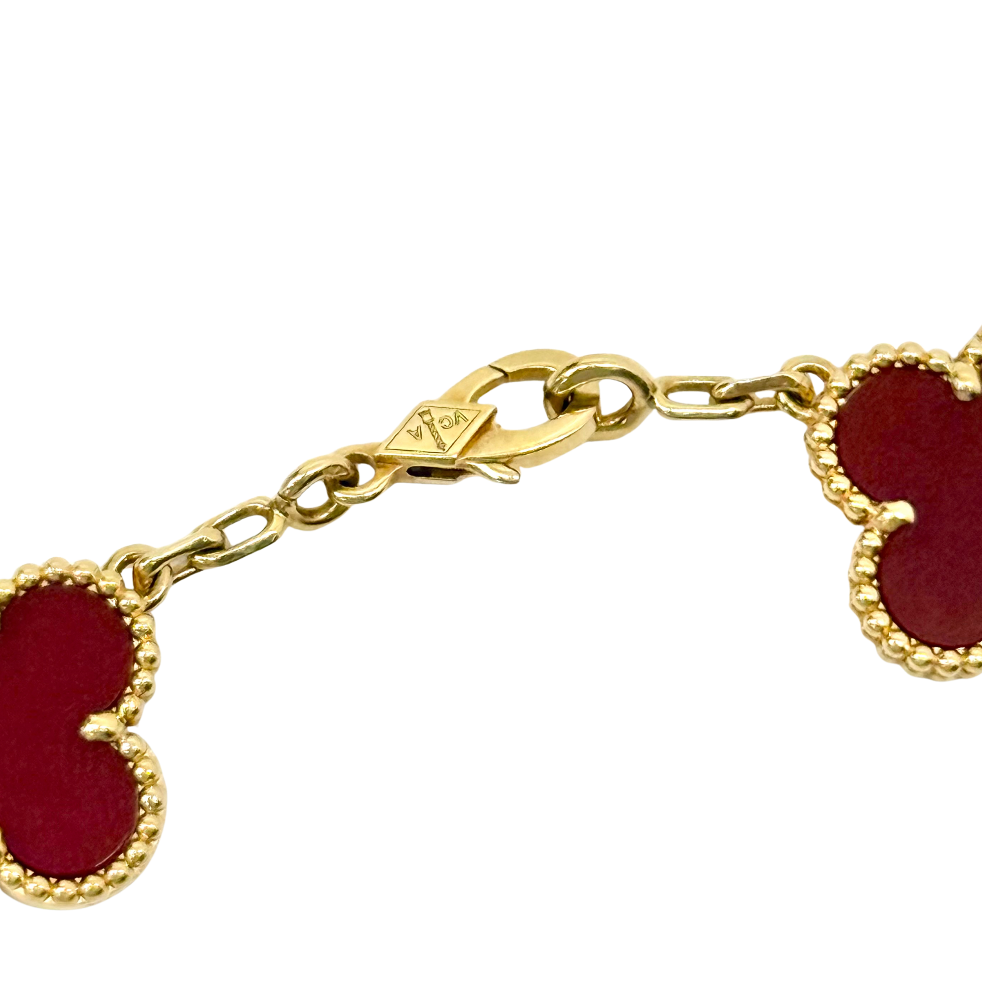 Goldtone bracelet chain with red enamel clover link, close-up view