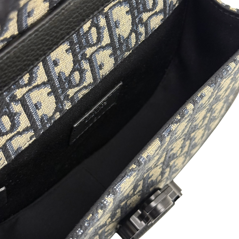 Black strap and clasp hardware on Dior patterned canvas crossbody bag
