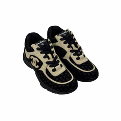 Black and beige Chanel lace-up sneakers, angled side view showing toe and swoop logo