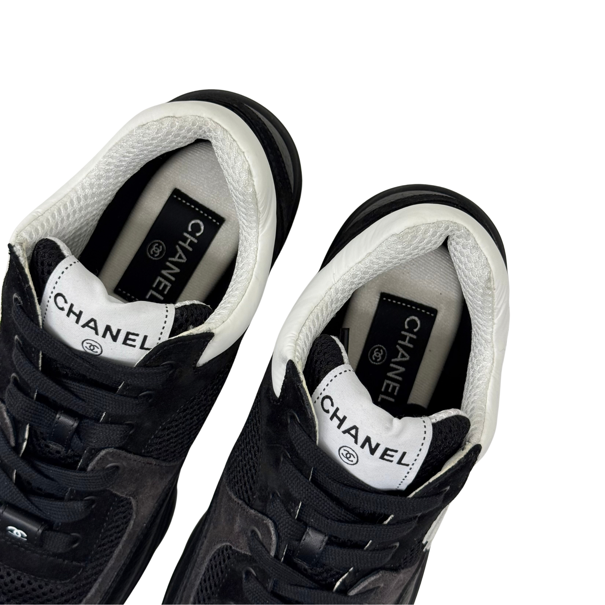 Black sneakers with white tongue label, padded interior, and lace-up closure.