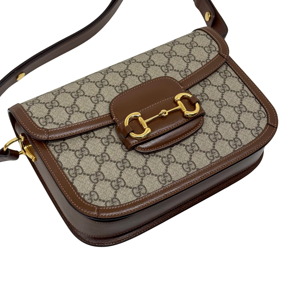 Pre-owned Gucci GG canvas shoulder bag angled view with brown trim and gold buckle