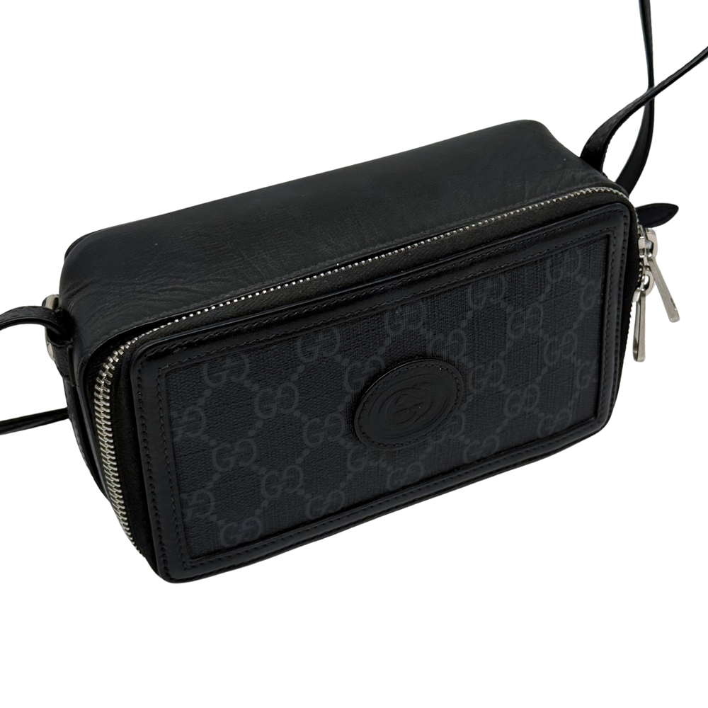 Small crossbody bag side view, black GG canvas with round logo emblem and zipper