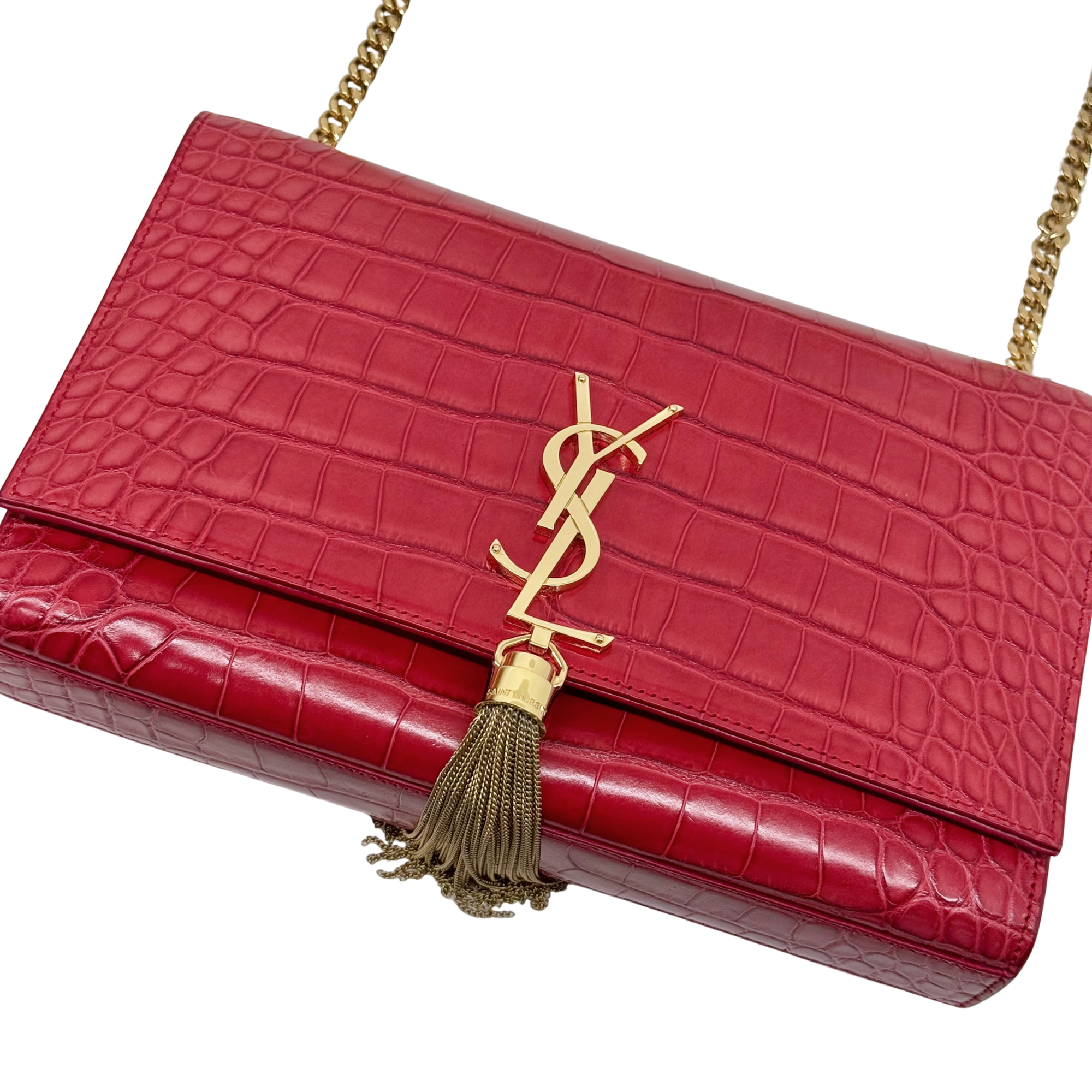 Red crocodile-pattern flap clutch with gold YSL logo, tassel, and chain strap