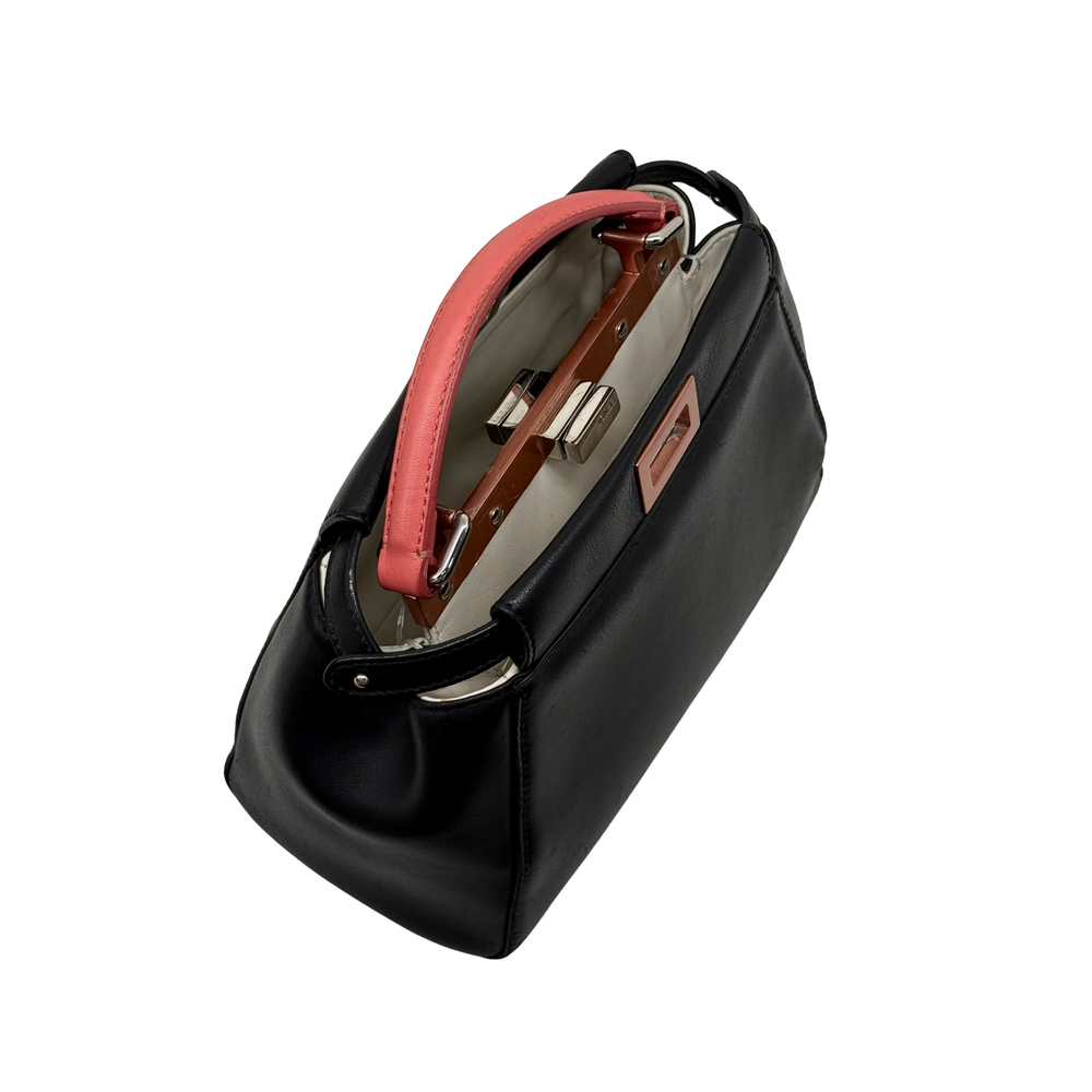 Side view of black handbag with red handle and exposed hardware